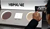 Person photographing a Samsung HBM4/4E memory display at a shareholder meeting in Suwon.