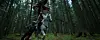 Two riders on horses move through a dim forest with tall trees and a mossy ground. A red creature hangs above them.
