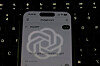 The OpenAI logo is reflected on the screen of a smartphone with the ChatGPT website displayed. [YONHAP]