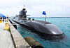 Korean submarine moored beside a pier at Naval Base Guam with a blue flag flying overhead.