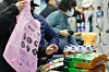 A customer puts groceries into a garbage bag, which is offered for bagging to be repurposed for trash disposal later, at a discount store in downtown Seoul on March 30. [NEWS1]