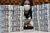 An official piles up dollar bills at Hana Bank's counterfeit notes response center in Seoul on April 3. [YONHAP]
