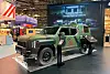 Camouflaged armored vehicle on display inside a trade show booth.