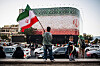 An Iranian child carries the national flag as the Iranian flag waves atop a building on June 14.