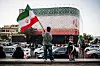An Iranian child carries the national flag as the Iranian flag waves atop a building on June 14.