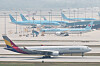 Passenger airplanes lined up on a runway at Incheon International Airport with a taxiing aircraft in the foreground.