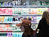 Two shoppers look at rows of Korean cosmetics displayed on lit shelves inside an Olive Young store.