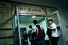 People gathered at the open entrance of a public office with a Hangul sign above the doorway.