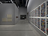 Museum or gallery corridor with framed art on one side and colorful wall-mounted artworks on the other.