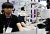 A robotic arm at a Seoul startup expo striking a tiny 0.4 mm pin during a precision demonstration.