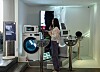 Student stands beside digital art installations at an LG exhibition in a white gallery space.