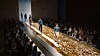 Samsung Bespoke Jet AI vacuum on a runway-style stage covered with gold-colored debris.