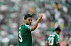 Raul Jimenez raises his arm in celebration in a Mexico World Cup match, with a teammate blurred in the background.