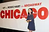 Broadway poster for Chicago with large red text and a woman standing in front of it.