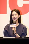 Woman speaking into a microphone in front of a Chicago event backdrop.