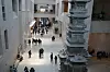 Crowds move through a large museum lobby with a multi-tiered pagoda structure in the foreground.