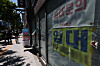 A lease notice is posted on a storefront window on a sunny street in Seoul.