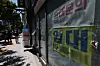 A lease notice is posted on a storefront window on a sunny street in Seoul.