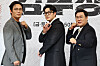 Three actors pose in front of a backdrop at a drama production event.
