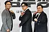 Three actors pose in front of a backdrop at a drama production event.
