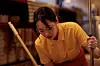 Person in a yellow shirt mopping a floor indoors.