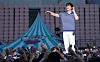 Singer Sung Si-kyung performs onstage as the crowd raises their hands at an outdoor concert.