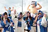 Fans in blue and white outfits pose together in front of a large inflatable figure at an outdoor concert.
