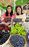 Models display domestically grown Korean grapes and blueberries at a Hanaro Mart in Seoul on June 28.