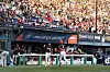 KIA Tigers players in the dugout cheer as a batter runs past after a home run at a packed baseball stadium.