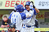 Two Samsung Lions baseball players in white uniforms celebrate on the field during a game.