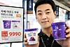 A Homeplus employee displays two ube ice cream containers beside a promotional poster.