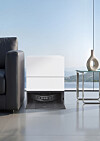 White LG robot vacuum station beside a sofa and side table in a minimalist living room.