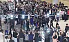 Large crowd of football fans surrounds a man moving through Incheon airport terminal.