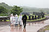 Visitors holding umbrella or wearing rain coats stroll inside a park on Jeju Island on June 24.