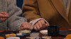 Close-up of two people’s hands resting on a table with small dishes and a black cup.