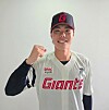 A smiling baseball player in a Lotte Giants uniform poses with a raised fist against a plain background.