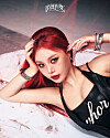 Red-haired woman in a black top reclines on a white textured surface and looks toward the camera.