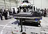 Workers perform a battery swap on an electric taxi inside a Pit In station.