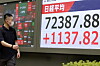 A passerby walks past a stock market indicator screen in Tokyo, Japan, on June 22.