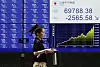 A passerby walks past a stock market indicator screen in Tokyo, on June 23.
