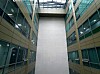 Symmetrical office atrium with glass walls, a tall white central shaft, and a skylight above.
