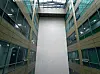 Symmetrical office atrium with glass walls, a tall white central shaft, and a skylight above.