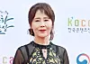 Woman standing in front of a branded event backdrop with Korean text and logos.