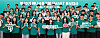 Large group of students in teal shirts holding signs and a banner on a stage.