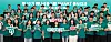 Large group of students in teal shirts holding signs and a banner on a stage.
