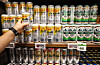 Shelves of Japanese beer cans in a Seoul supermarket, with a shopper reaching toward the display.