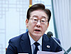 A South Korean president in a dark suit speaks into a microphone at a meeting table.