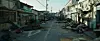 A damaged street with debris, collapsed buildings and muddy water on both sides.