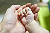 A baby hand is placed on a hand of an adult in a file photo.