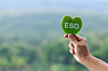 A hand holds green leaf with ESG text symbol.